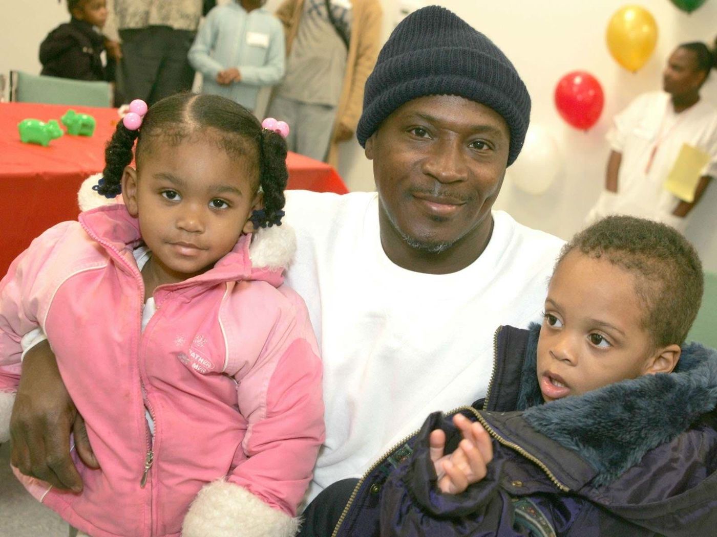 A father holds his two young children at a FreshMinistries community event.