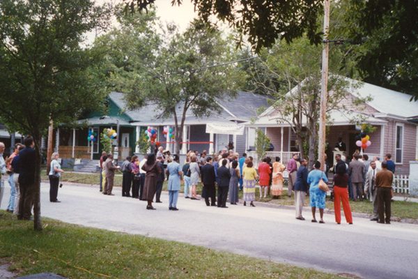 Neighbors gather in the street for a ribbon-cutting outside restored homes on Jacksonville's Eastside.