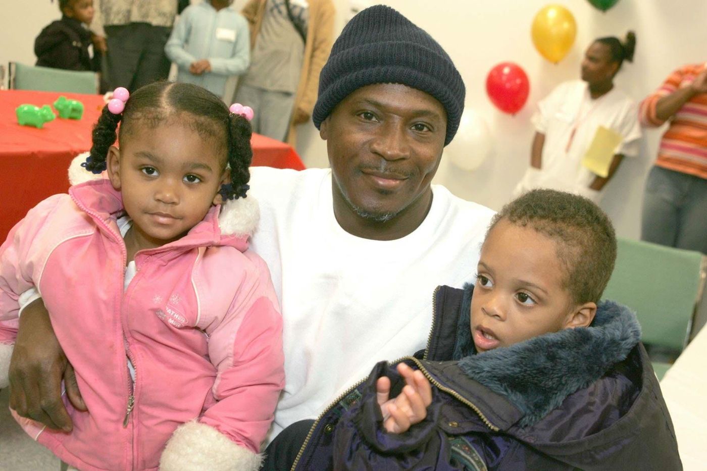 A father holding his two young children at a FreshMinistries community event.