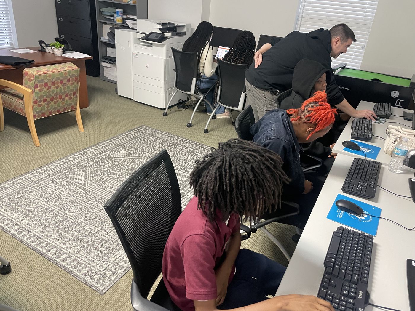 A mentor working with students in the computer lab at the Weaver Center