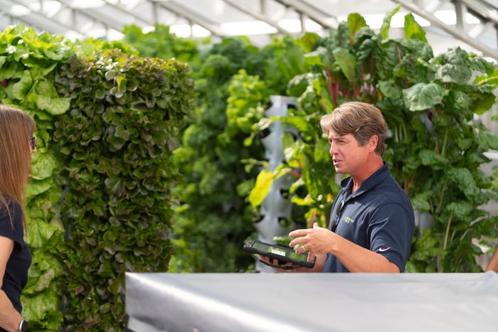 A NativeFresh grower walking visitors through the tower system, tablet in hand.