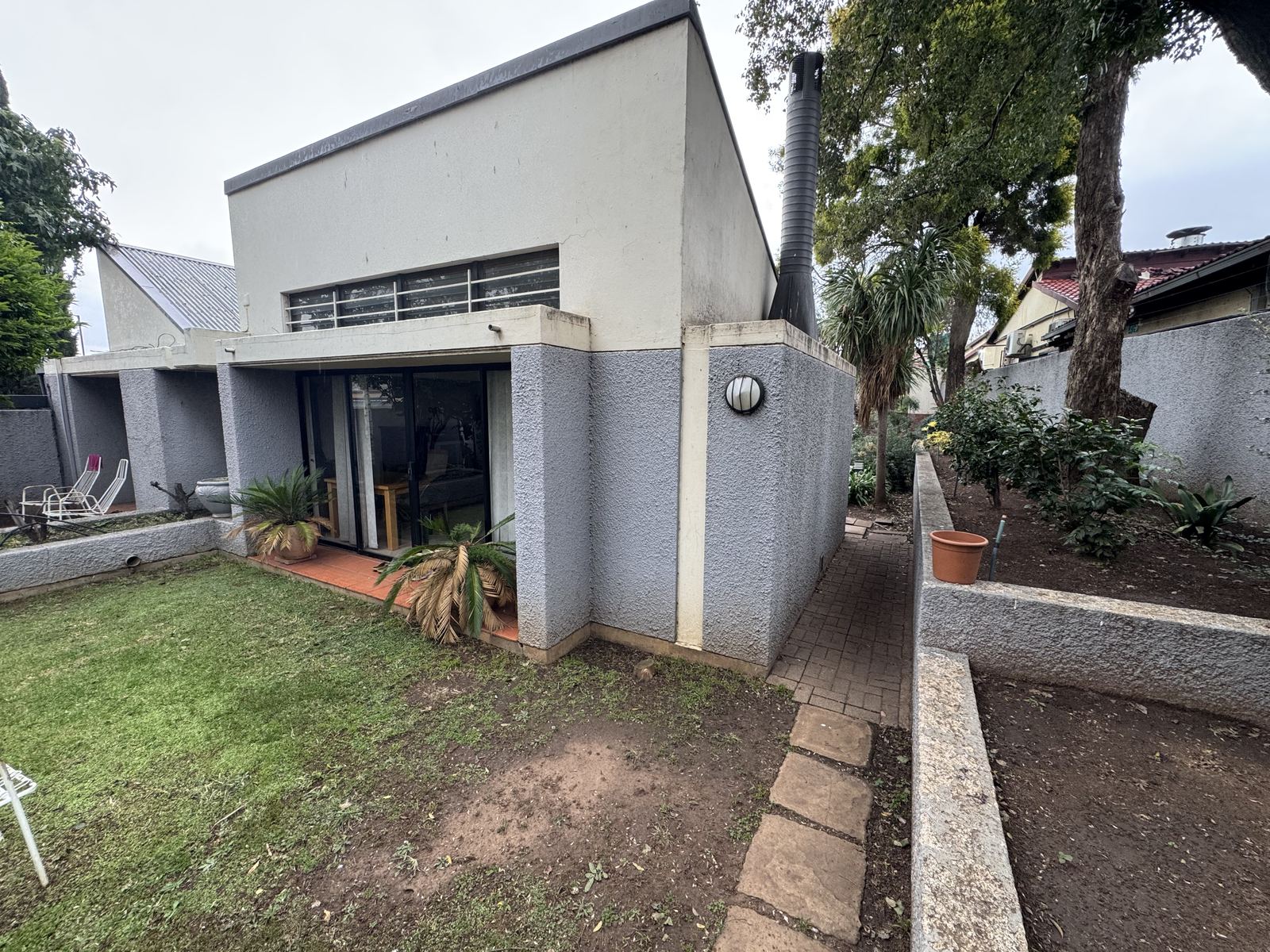 Archbishop Desmond Tutu's family home in Soweto, South Africa: a low grey house behind a lawn and garden.