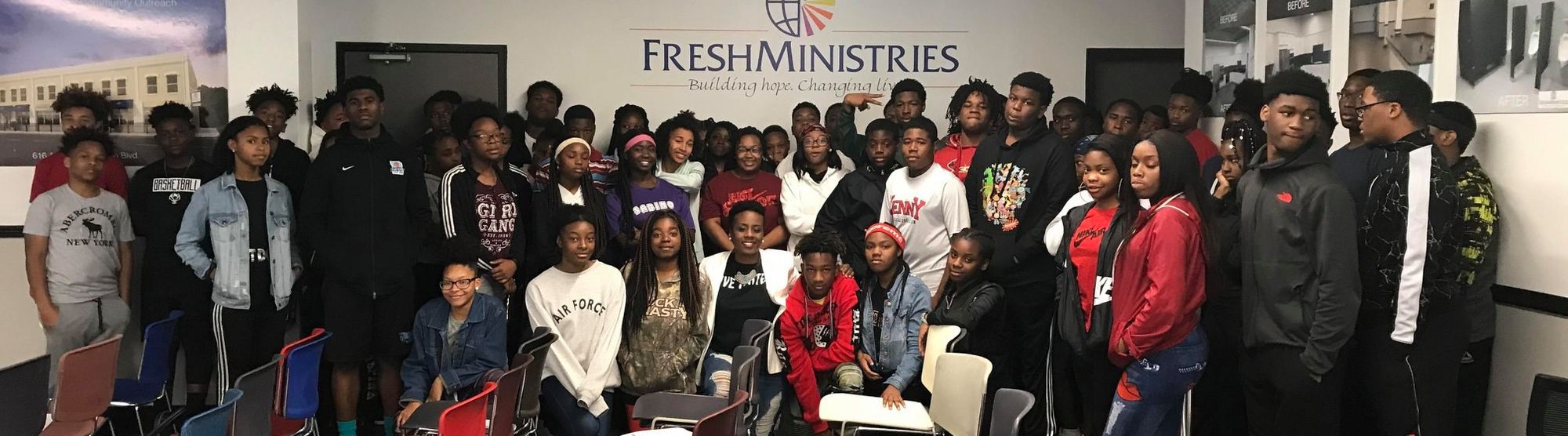 A large group of young people gathered beneath the FreshMinistries sign at a program event.