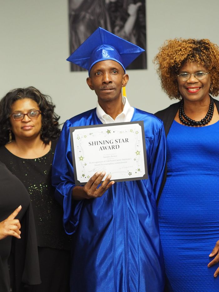 A graduate receiving an award alongside FreshMinistries staff.